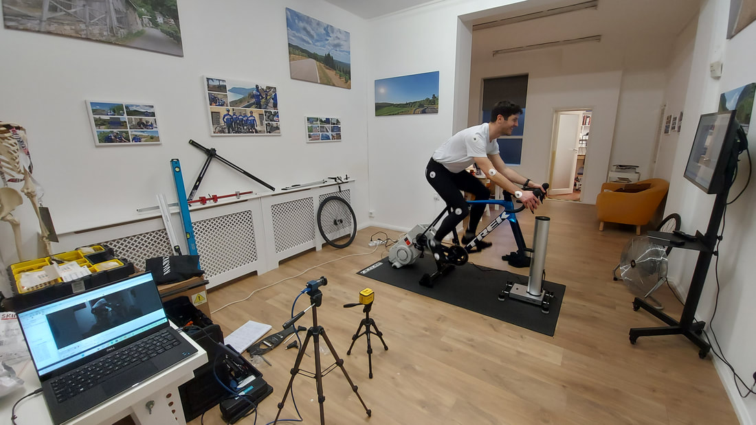 Cyclist pedalling during a bike fit session. Power meter display, turbo trainer and climb simulator.
