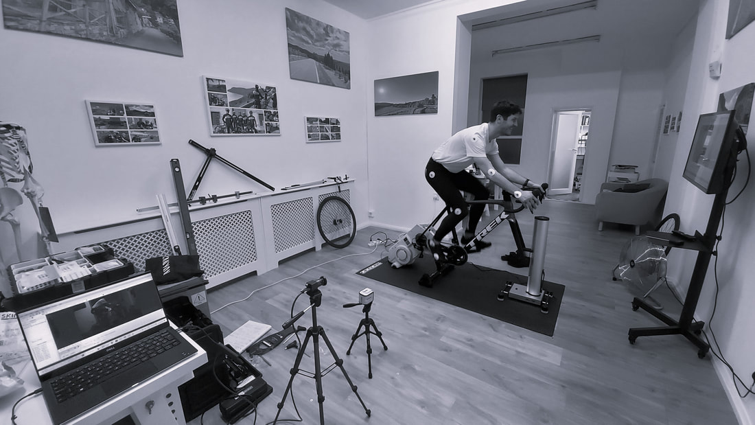 Cyclist pedalling during a bike fit session. Power meter display, turbo trainer and climb simulator.
